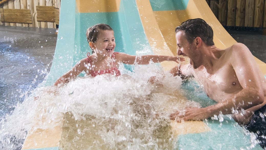 A father and daughter comes down from a water slide 