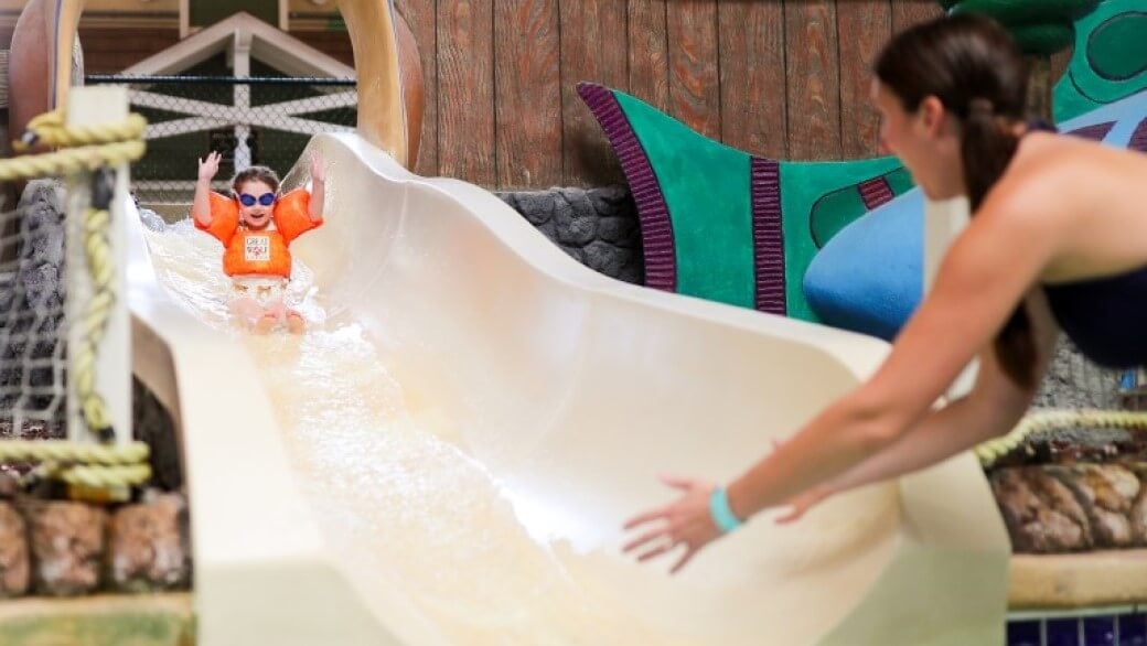 A small child floats down a water slide at a Great Wolf Lodge indoor water park.